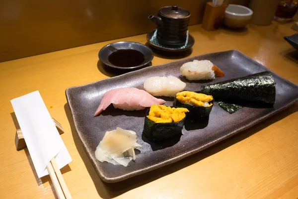 Verse sushi op een zwarte plaat met stokjes — Stockfoto