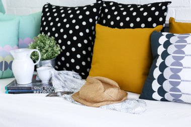 arka planda renkli yastıklar bir kanepe ile beyaz tuğla duvar