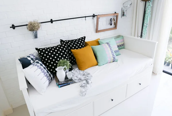 Almohadas de colores en un sofá con pared de ladrillo blanco en el fondo —  Fotos de Stock