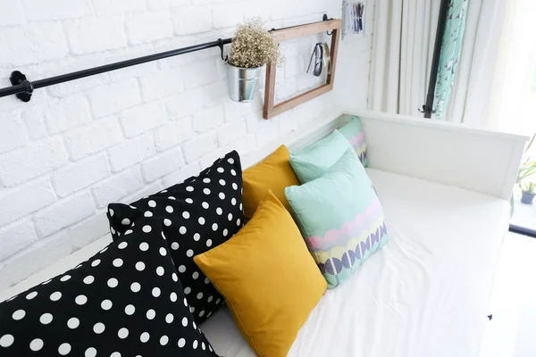 Almohadas de colores en un sofá con pared de ladrillo blanco en el fondo — Foto de Stock