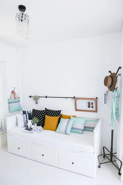 Cuscini colorati su un divano con parete in mattoni bianchi sullo sfondo — Foto Stock