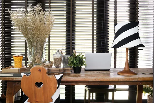 Mesa de trabalho de madeira com um laptop, lâmpada vintage e travesseiro — Fotografia de Stock