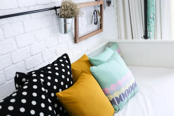 Kleurrijke kussens op een sofa met witte bakstenen muur op achtergrond Stockfoto