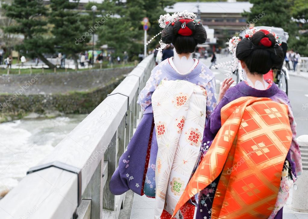 Two geisha walking on a bridge in Arashiyama, Japan