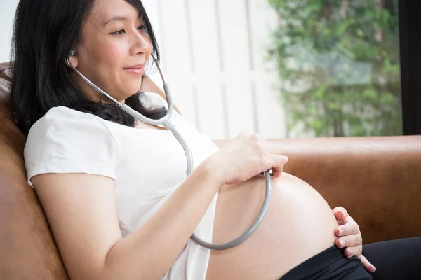 Zwangere vrouw met behulp van stethoscoop — Stockfoto