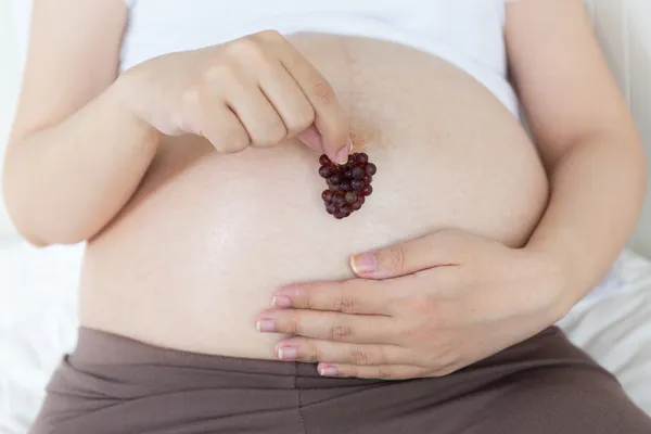 Pregnant belly with cherry — Stock Photo, Image