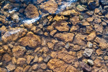 Taş tabanlı arka plan dokusu. Suyun yüzeyinin altındaki çakıl taşlarının soyut deseni. 