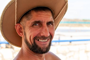 Sakallı ve sombrero şapkalı, gülümseyen orta yaşlı, yakışıklı bir adam. Acımasız adam gülümsüyor.