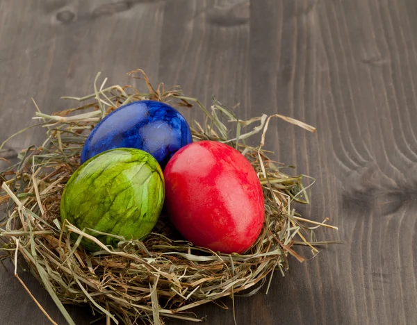 Œufs de Pâques dans le nid de foin sur bois foncé — Photo