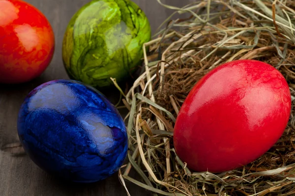 Œufs de Pâques dans le nid de foin sur bois foncé — Photo