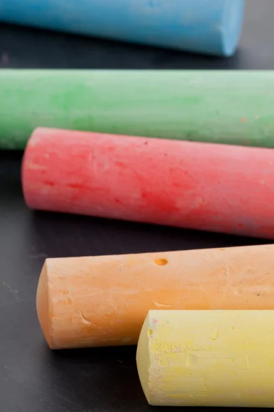 Colorful pieces of chalk on blackboard — Stock Photo, Image