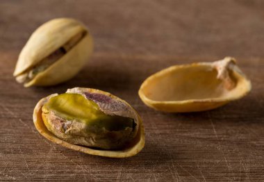 Tuzlu, kavrulmuş, ahşap zemin üzerinde yeşil şam fıstığı, sağlıklı yiyecek atıştırması, seçici odaklanma.