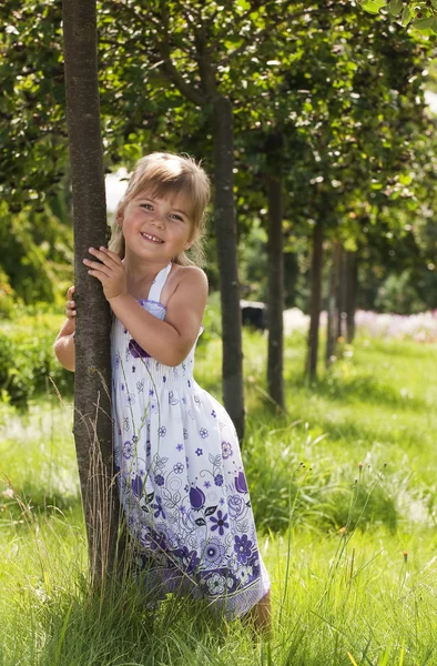 Little girl standing beside the tree in the park — Stock Photo, Image