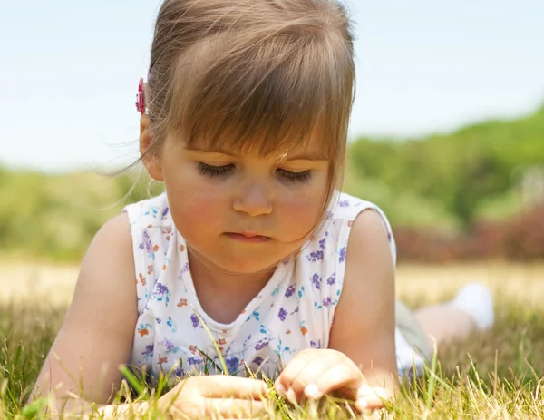 Little girl lying on grass in the park — Stock Photo, Image