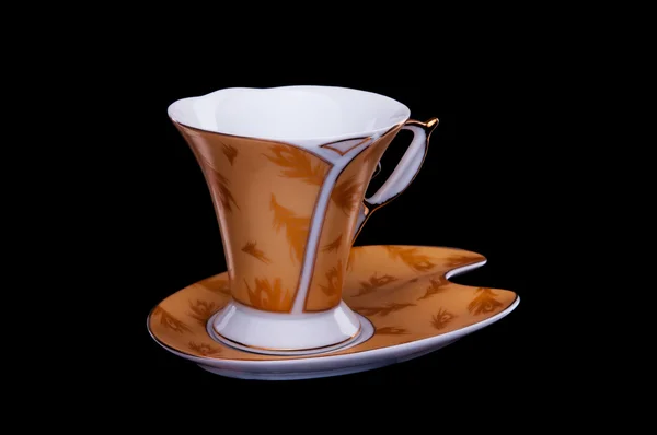 Taza de café dorado con platillo sobre fondo negro — Foto de Stock