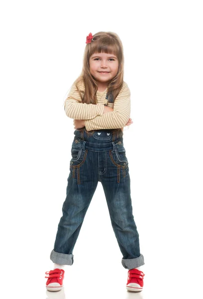 Söt liten flicka klädd i jeans övergripande poserar i studio och smil — Stockfoto