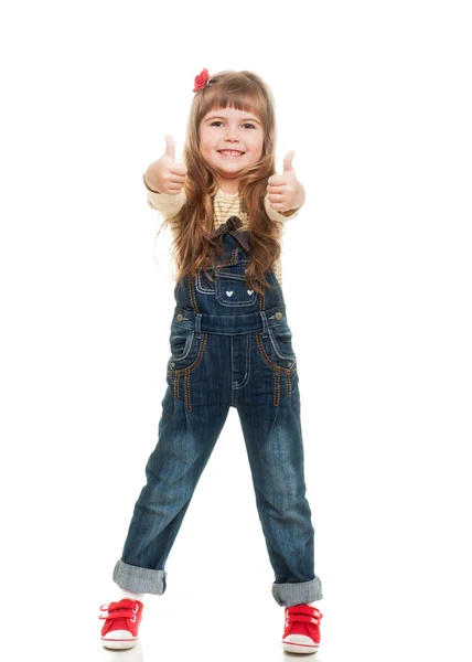 Cute little girl wearing jeans overall posing in studio showing — Stock Photo, Image