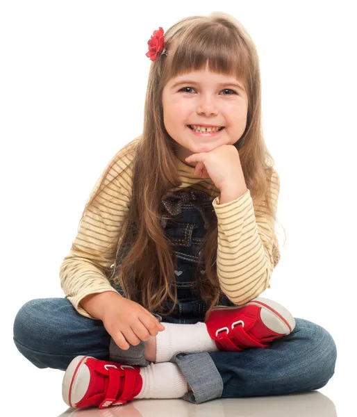 Cute little girl wearing jeans overall sitting on the floor and Stock Picture