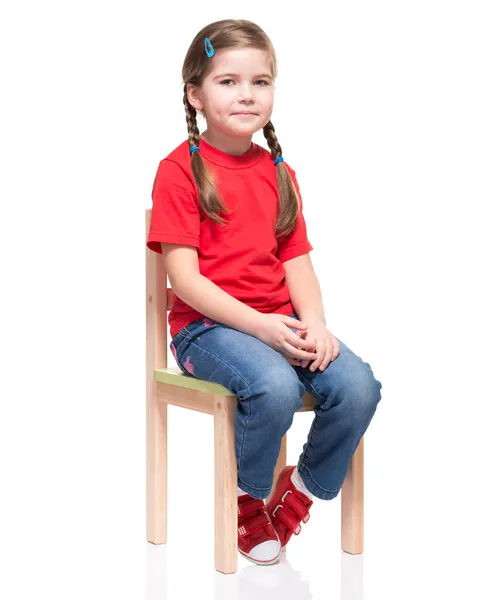 Lilla flickan bär röda t-kort och poserar på stol — Stockfoto