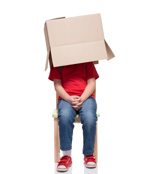 Child sitting on a chair with big box covered head — Stock Photo, Image