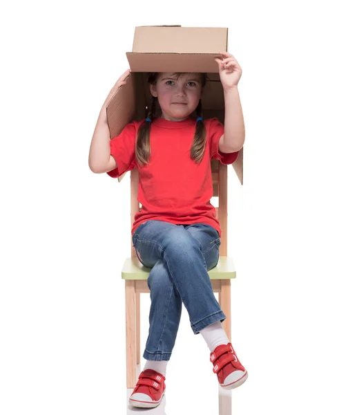 Child sitting on a chair with big box covered head — Stock Photo, Image