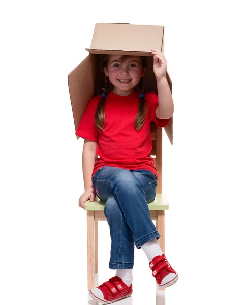 Enfant assis sur une chaise avec une grosse tête couverte de boîte — Photo