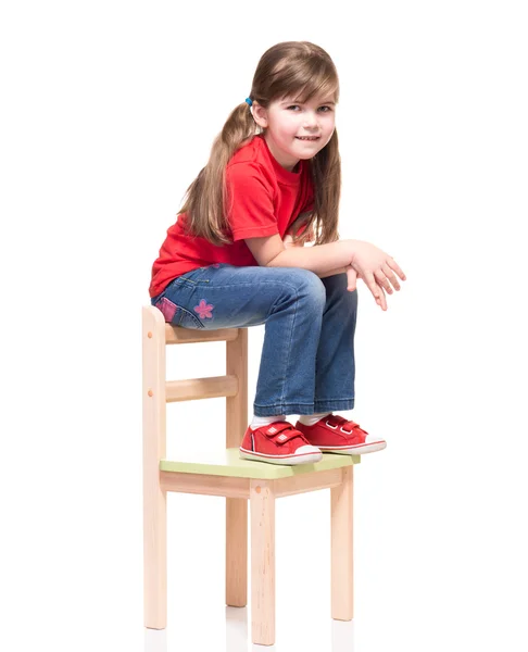 Little girl wearing red t-shirt and posing on chair — Stock Photo, Image