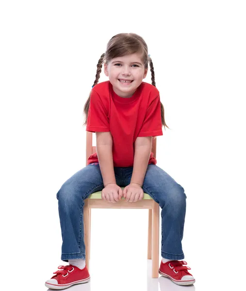 Menina vestindo camiseta vermelha e posando na cadeira — Fotografia de Stock