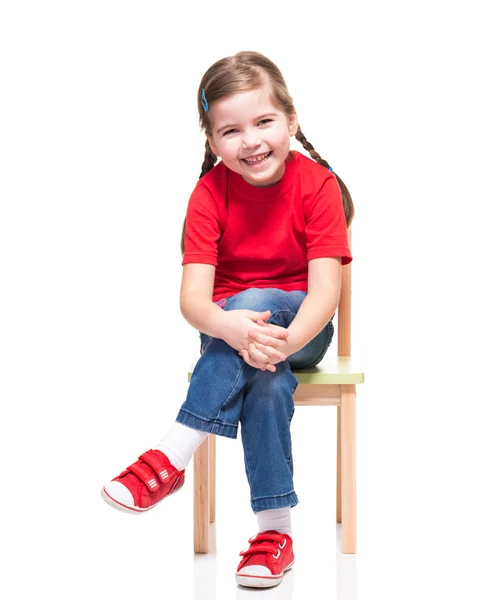 Little girl wearing red t-short and posing on chair Royalty Free Stock Photos