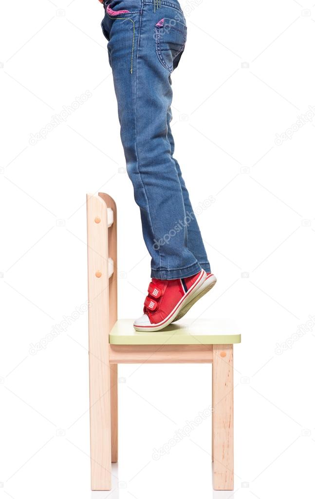 child's feet standing on the little chair on tiptoes