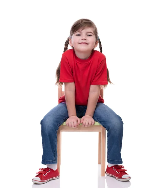 Menina vestindo camiseta vermelha e posando na cadeira — Fotografia de Stock