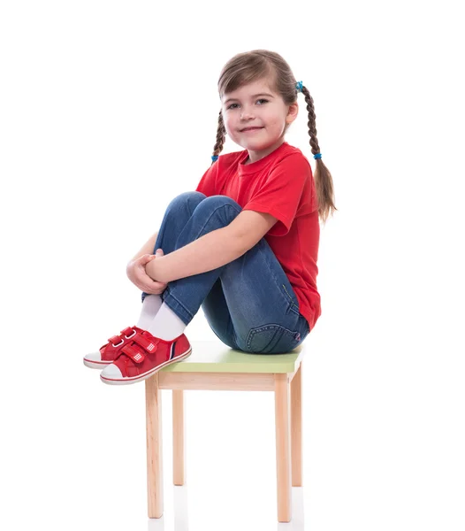Malá holka na sobě červené tričko a pózování na židli — Stock fotografie