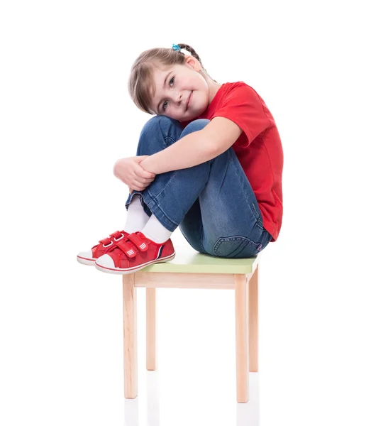 Kırmızı t-shirt giyen ve sandalye üzerinde poz küçük kız — Stok fotoğraf