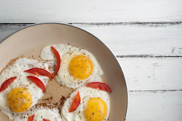 Горячая сковорода с жареными яйцами и маленькими кусочками помидоров Лицензионные Стоковые Изображения