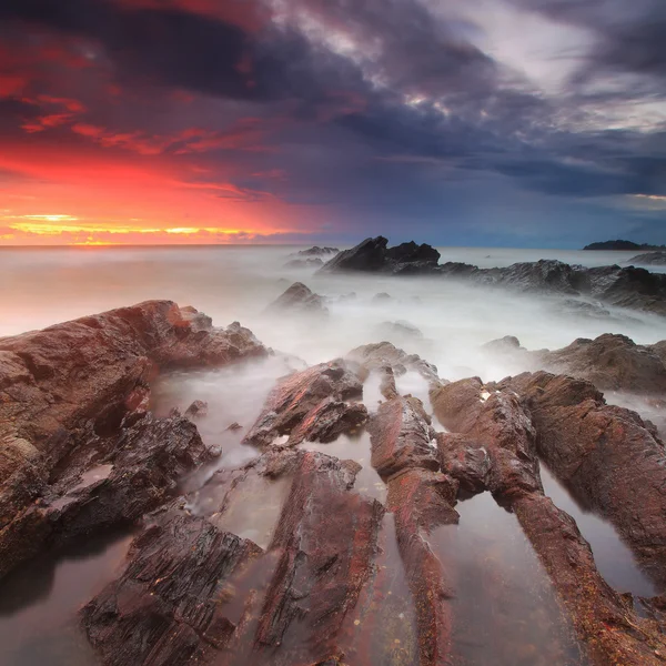 Lever de soleil dramatique sur le rivage rocheux — Photo