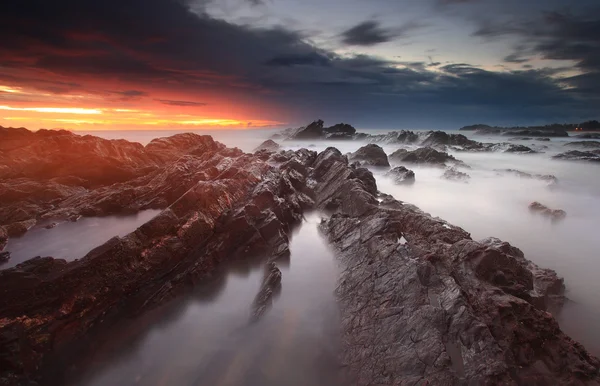 Dumanlı Denizi kayalık sahil üzerinde dramatik gündoğumu