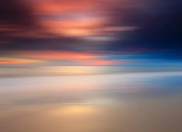 Farbenfroher Sonnenuntergang am Strand in Langzeitbelichtung lizenzfreie Stockbilder