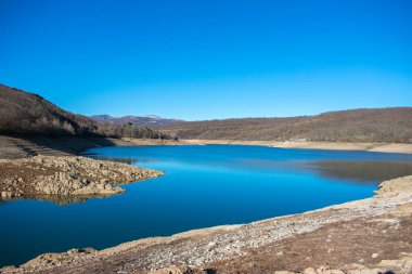 Su ve mavi gökyüzü olan bir dağ gölü.