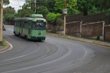 a classic green  tram running on rails