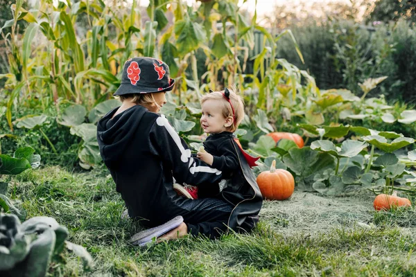 Concetto di vacanza e infanzia - I bambini felici nei costumi di Halloween giocano in giardino la vigilia di Halloween — Foto Stock