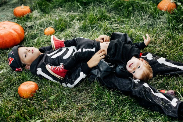 Un bambino e sua sorella giocano sull'erba nel giardino la vigilia di Halloween. Il concetto di vacanza, tradizioni e infanzia — Foto Stock