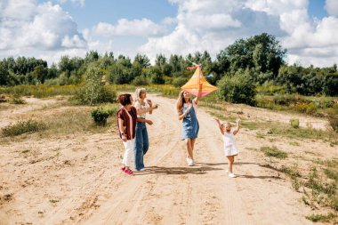 Sevimli küçük bir kız ve ailesi uçurtma uçuruyor. Aile, nesil, birlikte zaman, ilişkiler.