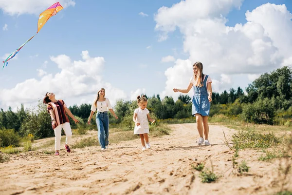 魅力的な少女と彼女の家族は凧を飛んでいます。家族、世代、時間、関係 — ストック写真
