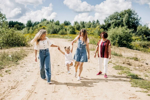 同一家几代妇女在城外的一条土路上散步，享受着一起度过的时光 — 图库照片