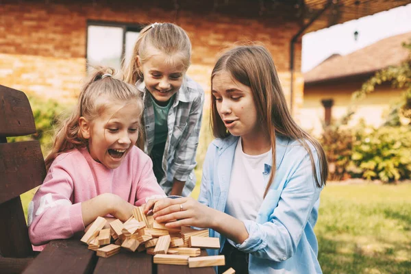 三个女朋友在屋外玩木制棋盘游戏. — 图库照片