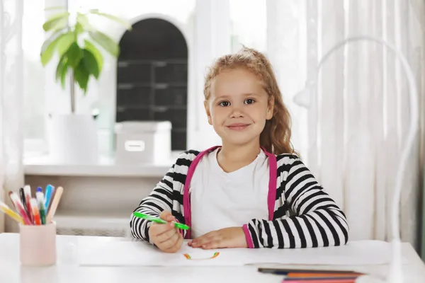 Retrato de una chica encantadora que dibuja un arco iris en un álbum con lápices de colores. Tareas, formación en el hogar, distancia social —  Fotos de Stock
