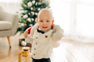 Noel arifesinde ya da yeni yıl arifesinde bir Noel ağacının arka planında gülümseyen şirin bir bebeğin portresi