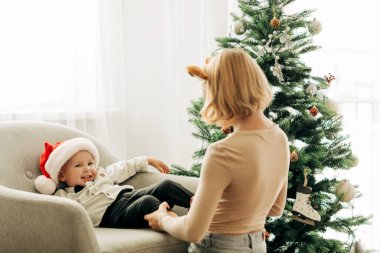 Erkek ve kız kardeş Noel ağacının yanındaki sandalyede birlikte oynuyorlar. Çocuklar birlikte eğleniyor. Noel ve Yeni Yıl kavramı