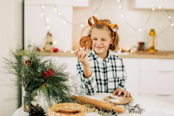 Portrait of a joyful girl holding a Christmas decorative cookie in her hand. Preparation for the holidays, Christmas spirit, Christmas treats — Stock Photo, Image