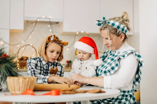 Happy family mother and children son and daughter bake cookies for Christmas. Christmas spirit, a family tradition — Stock Photo, Image